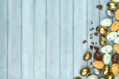 Paskalya tebrik kartı, takvim, poster, afiş. Çikolata, altın, dekoratif yumurta, açık mavi ahşap tahtalar üzerinde