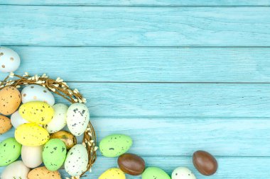 Paskalya tebrik kartı, takvim, poster, afiş. Çikolata, altın, dekoratif yumurta, açık mavi tahta çelenk