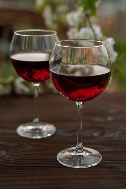 Güzel bir bahar gününde, tahta bir açık havada, uzun, kırmızı şarap kadehleriyle dolu bir hayat. Kiraz çiçekleriyle çiçek açan dallar. Seçili odak