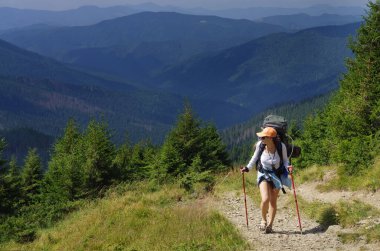 Sırt çantalı bir kadın turist dağ yamacına tırmanıyor. Turizm tatili aktivitesi. 17 Kasım 'da Ulusal Yürüyüş Günü