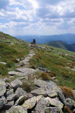 Yürüyüşçüler kayalık bir yolda dağlara tırmanıyor. Turizm, açık havada tatil aktiviteleri. 17 Kasım 'da Ulusal Yürüyüş Günü