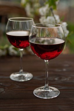 Güzel bir bahar gününde, tahta bir açık havada, uzun, kırmızı şarap kadehleriyle dolu bir hayat. Kiraz çiçekleriyle çiçek açan dallar. Seçili odak