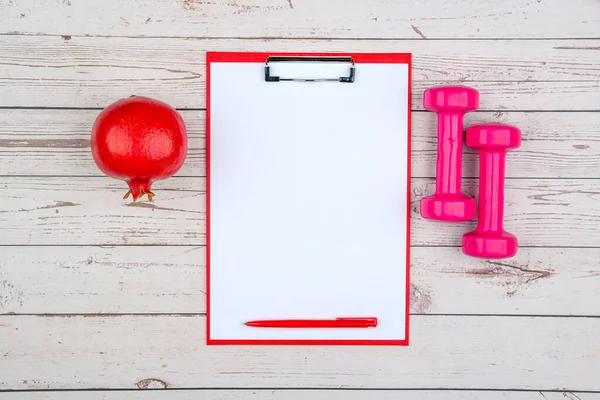 Eğitim ekipmanları ve nar ile sağlıklı yaşam tarzı çalışma konsepti. Adet sırasında uyum sağlama ve spor yapma fikri. Boş kopyalama alanı kırmızı pano üzerinde maket.