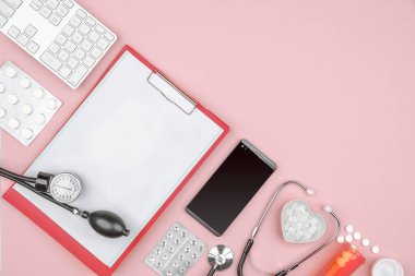 Sağlık hizmeti, akıllı telefon, internet yardımı, haplar, klavye. Saflık, beyaz ve pembe renk, düz yatış. Boş kopyalama alanı, kırpma tahtası maketi