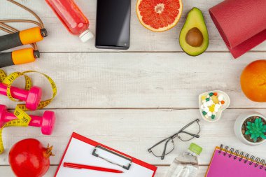 Sağlıklı yaşam tarzı kavramı. Kalp şeklinde tabakta, suda, meyvelerde, yoga minderinde, akıllı telefon ve spor aksesuarlarında diyet takviyesi. Boş kopyalama alanı.