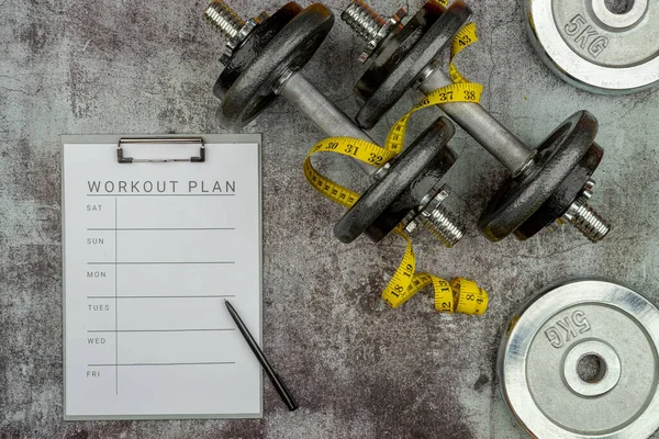 Sağlıklı yaşam tarzı güçlü kaldırma konsepti tutuş ile demir olimpiyat ağırlık plakalarını beton zemine fırlattı. Çalışma planı sekmesi olan klip tahtası, mezura.