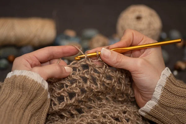 Female hands crafting knitting with crochet. Hobbies, handicrafts and handmade work. Threads, balls of yarn, skeins, bobbins, spools.