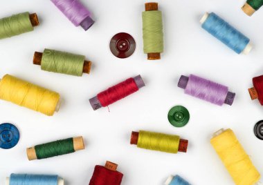 Bobins, çok renkli iplik makaraları, beyaz arka planda dikiş aksesuarları..