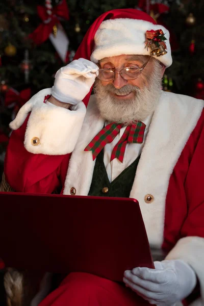 圣诞老人带着手提电脑萤火虫和圣诞树木屋内喜庆的室内空气 新年喜庆的气氛 圣诞的精神 长得象真的白胡子的老人 圣诞老人 — 图库照片