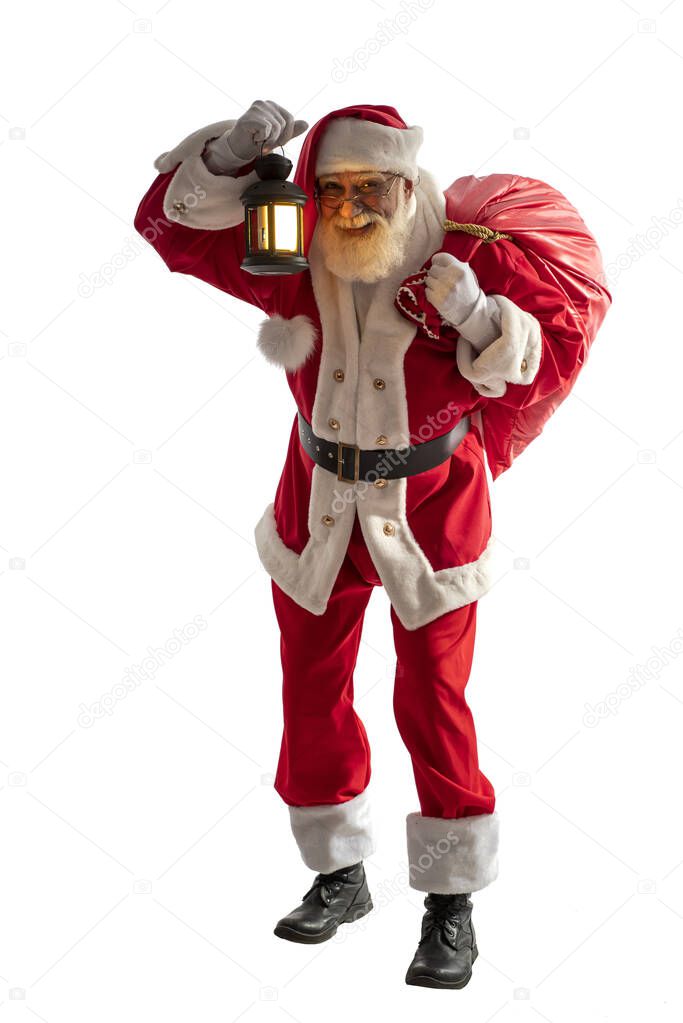 Santa Claus on white background isolated. Senior actor old man with a real white beard in the role of Father Christmas. Male character stands upright full-length holding a bag of gifts and a lantern