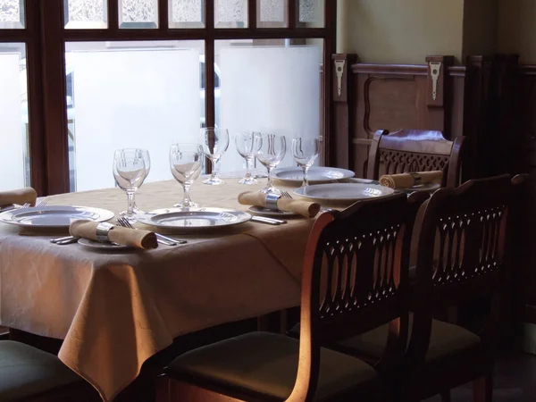 Luxurious table setting in an expensive restaurant, old-fashioned cafe. Wooden furniture, wineglass, drapery, silver dishes, empty plates, beautiful tablecloths. Without people. Catering business.