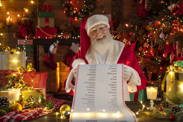 Noel Baba Güzel Liste Parşömeni. Ahşap evin içindeki şenlikli iç mekan, Noel 'in neşeli ruhu. Gerçek beyaz sakallı son sınıf öğrencisi Noel Baba kostümü giyiyor..