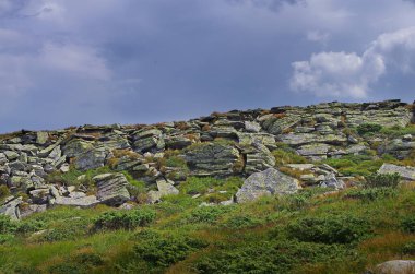 Yüksek dağlar, kayalar, taşlar. Dağ panoramik manzarası, bulutlar ve mavi gökyüzü. Turizm, seyahat, yeni deneyimler