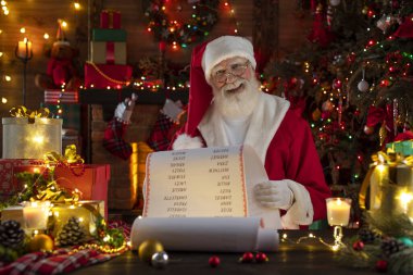 Noel Baba Güzel Liste Parşömeni. Ahşap evin içindeki şenlikli iç mekan, Noel 'in neşeli ruhu. Gerçek beyaz sakallı son sınıf öğrencisi Noel Baba kostümü giyiyor..