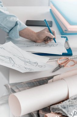 Yaratıcı kadın moda tasarımcısı taslaklar çiziyor. Bir dikiş atölyesinde yaşam tarzı sahnesi. Kadın terzi, modaya uygun elbise resimleri çiziyor.