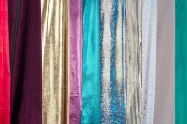Kumaş koleksiyonu, çok renkli perdeler, perdeler, yatak örtüleri. Sırayla katlanmış çeşitli kumaşlar. Yaratıcılık için malzemeler, dikiş malzemeleri.