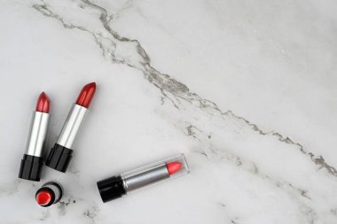 Kadın aksesuar konsepti, kırmızı açık ruj siyah ve gümüş tüp beyaz mermer yüzey. Reklam kozmetiği için uygun kompozisyon, metin için boş kopya alanı