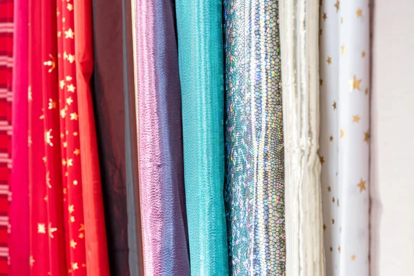 Collection of fabric, multicolored drapery backdrop, curtains, bed linens. Set of assorted fabrics folded in a row. Materials for creativity, sewing clothes