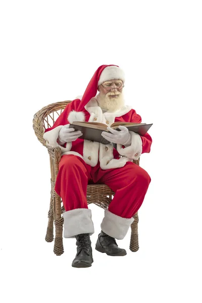 白色背景的圣诞老人被隔离了 老男演员 留着真正的白胡子 扮演圣诞老人的角色 坐在柳条椅上看书 — 图库照片