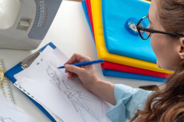 Yaratıcı kadın moda tasarımcısı taslaklar çiziyor. Bir dikiş atölyesinde yaşam tarzı sahnesi. Kadın terzi, modaya uygun elbise resimleri çiziyor.