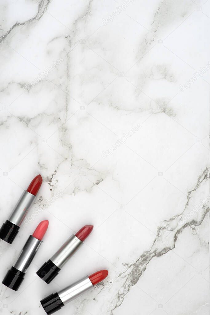 Woman accessories concept, red open lipstick in black and silver tube on white marble surface. Composition suitable for advertising cosmetics, empty copy space for text