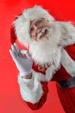 Noel Baba kırmızı arka planda parmağıyla işaret ediyor. Noel Baba 'nın doğal beyaz sakallı, son sınıf öğrencisi, yaşlı bir adam. Reklamcılık için neşeli bir karakter