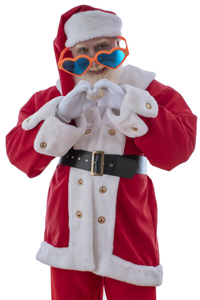 Xmas Santa Claus with funny heart-shaped sunglasses on white isolated background. Emotional senior male model old man with a natural white beard. Joyful character for Christmas season advertising