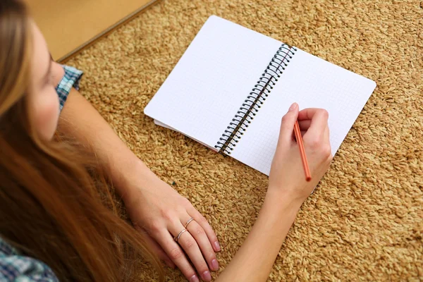 Mãos de mulher loira deitada no chão do tapete segurando lápis — Fotografia de Stock