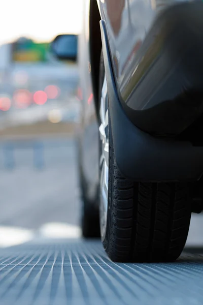 Dark automobile standing on steel floor view from below — Stock Photo, Image