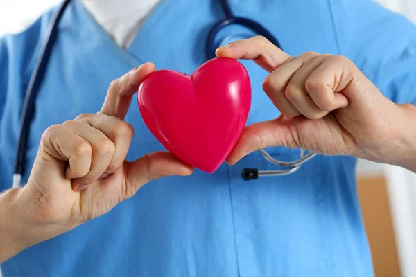 Médico de medicina masculino vestindo uniforme azul segurar nas mãos brinquedo vermelho — Fotografia de Stock