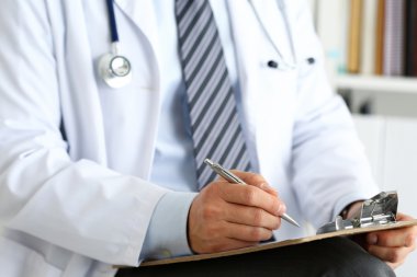 Erkek doktor elinde gümüş kalemle yazı tutuyor.