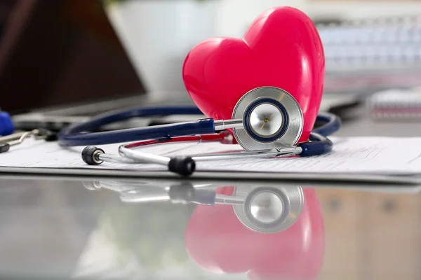 Medical stethoscope head and red toy heart lying on cardiogram c — Stock Photo, Image