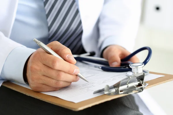 Médico masculino mano sosteniendo pluma de plata escritura — Foto de Stock