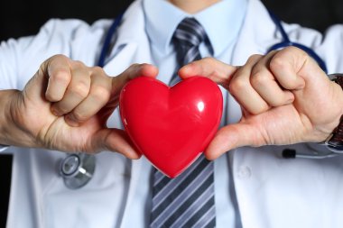 Tutun ellerini kırmızı oyuncak kalbinde giyen erkek tıp doktor