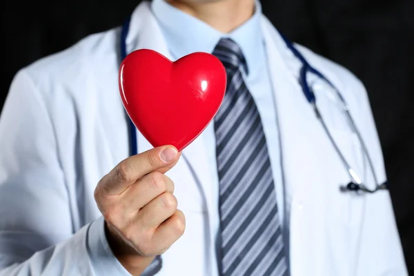 Αρσενική ιατρική γιατρός φοράει κρατήστε στα χέρια παιχνίδι κόκκινο καρδιά — Φωτογραφία Αρχείου