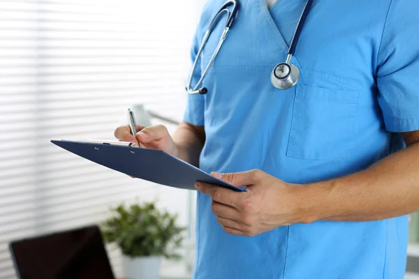 Médico masculino mano sosteniendo pluma de plata escribiendo algo —  Fotos de Stock