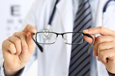 Erkek doktor elleri siyah gözlük takıyor.