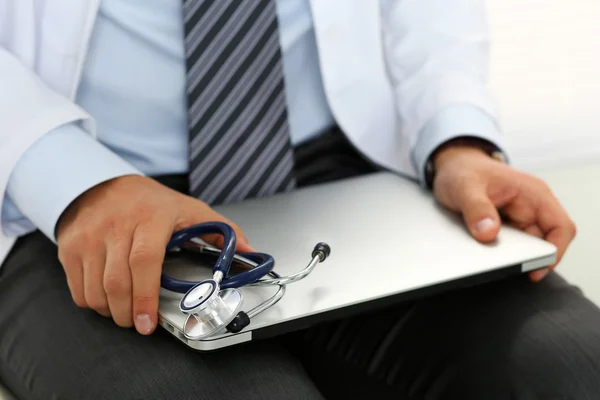 Hombre médico de la medicina sentarse y sostener en las rodillas portátil de plata — Foto de Stock