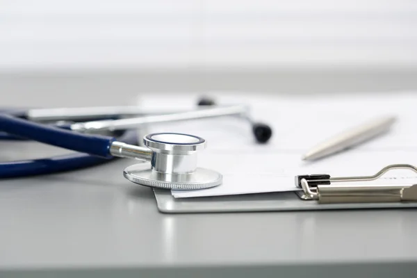 Stethoscope head lying on medical form on clipboard pad — Stock Photo, Image