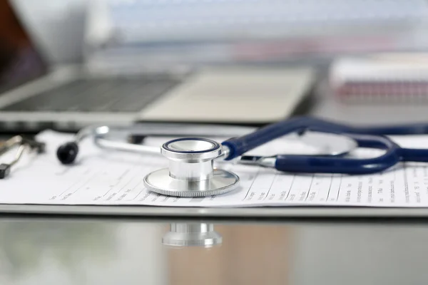 Stethoscope head lying on medical form on clipboard pad