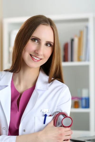 Bella sorridente femmina medico stand in ufficio tenendo stethosc — Foto Stock