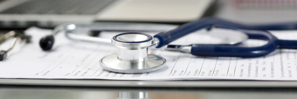 Stethoscope head lying on medical form on clipboard pad