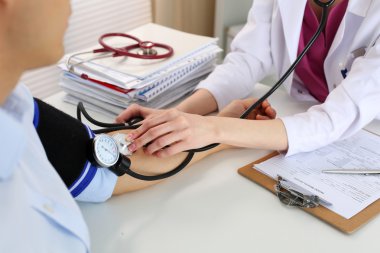 Erkek hastaya kan basıncını ölçen kadın doktor elleri