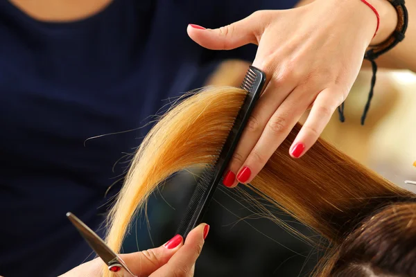 Женский парикмахер держит в руке прядь светлых волос — стоковое фото