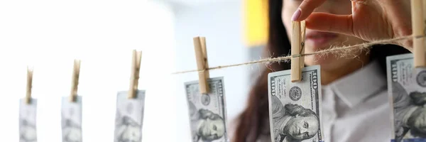 Manos femeninas tomando billete de 100 dólares de la línea de ropa — Foto de Stock