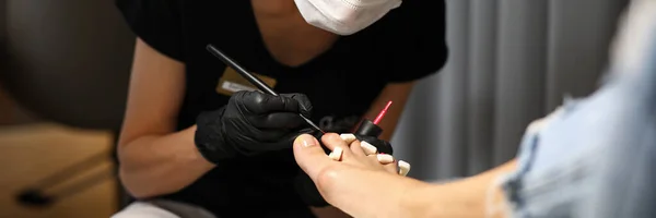 Pediküre-Meister mit Masken und Handschuhen lackiert Nägel — Stockfoto