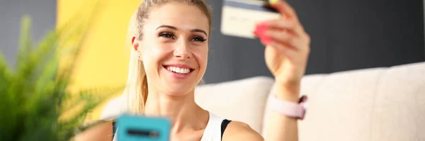 Mooie vrouw kijkt naar credit card en lacht — Stockfoto