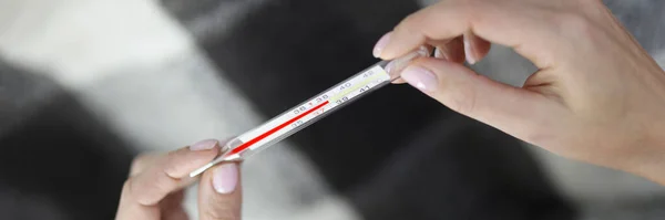 In womens hands a thermometer with temperature of 38.