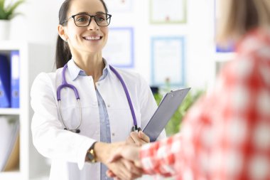 Gülümseyen doktor hastayla el sıkışıyor.