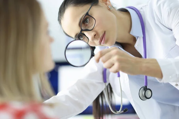 Läkaren undersöker patientens ansikte genom förstoringsglas — Stockfoto